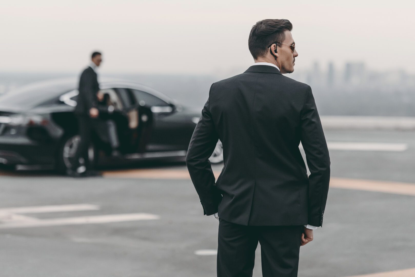 A man in a suit and tie standing next to a car.