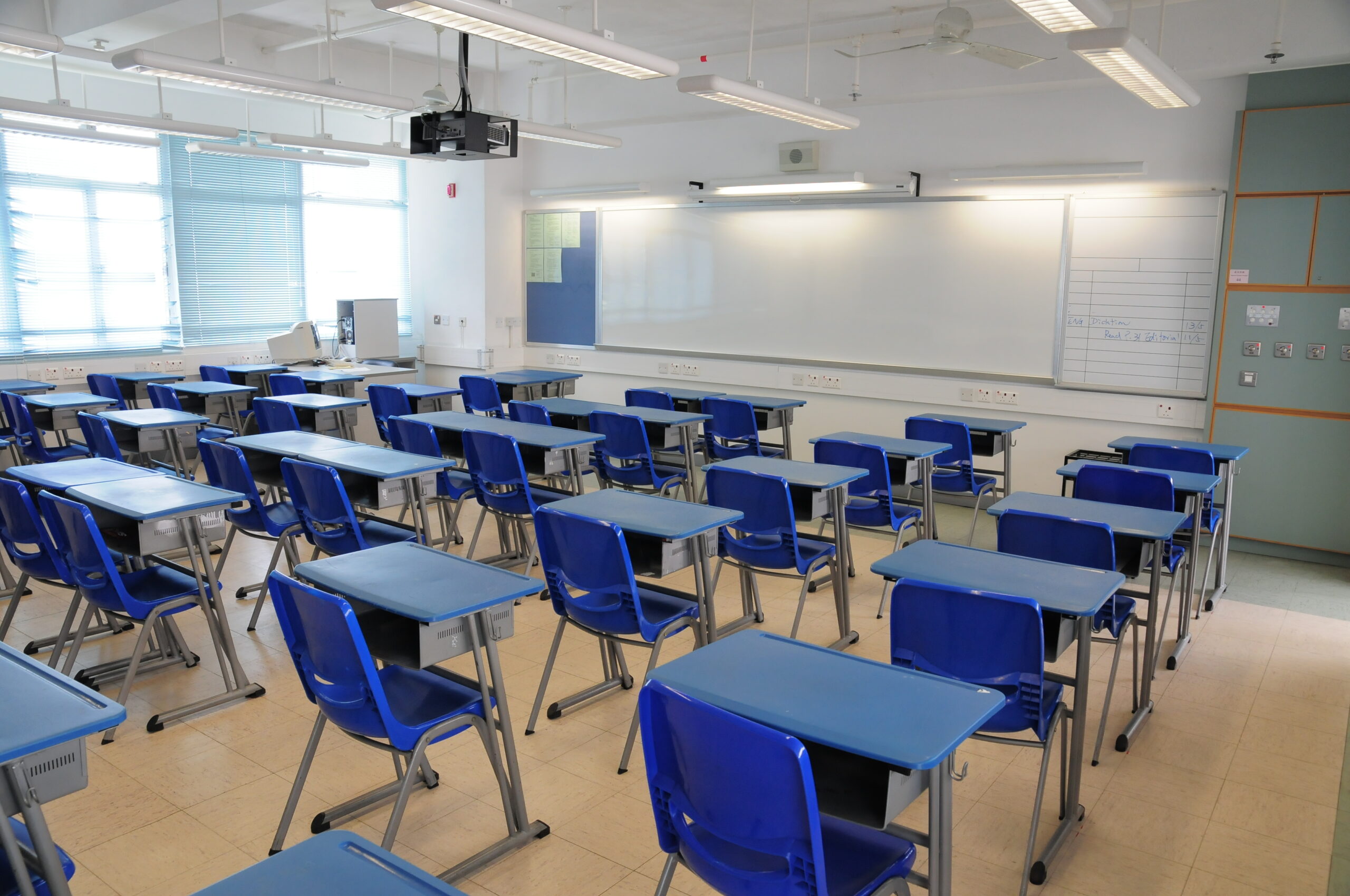 A classroom with blue chairs and desks in it